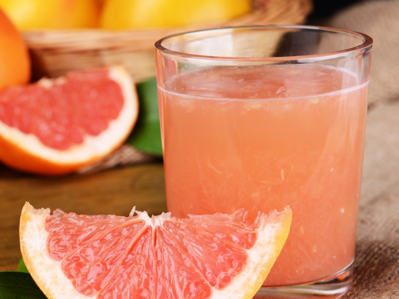 A Glass of Grapefruit Juice and Grapefruit Slice on a Wooden Table