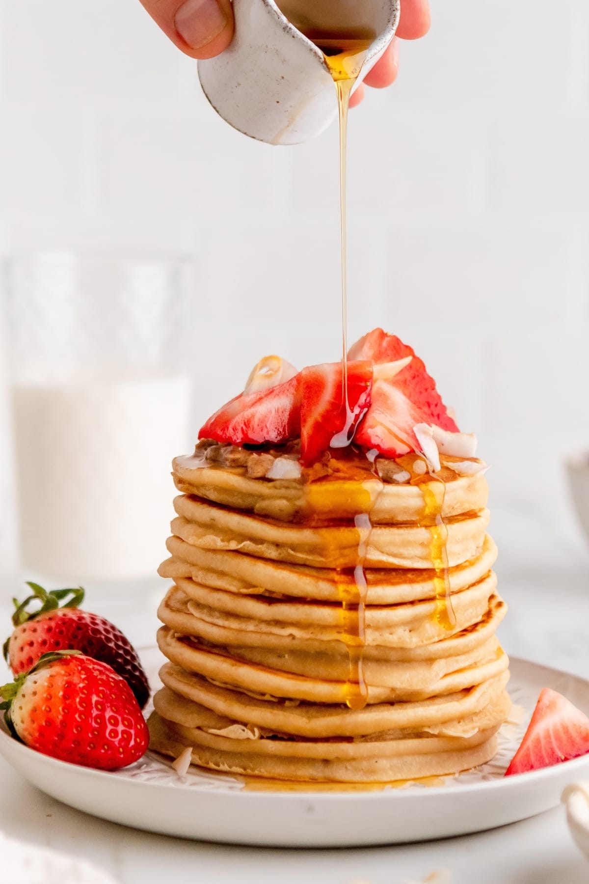 How to Freeze and Reheat Pancakes featuring Stack of Fresh Cooked Pancakes Topped With Fresh Strawberries, Poured With Syrup