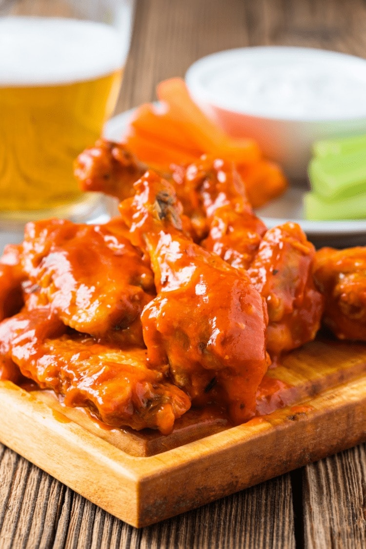 Buffalo chicken wings served on a wooden cutting board.