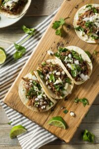 Homemade Pork Carnitas with Herbs and Lime in a Wooden Cutting Board