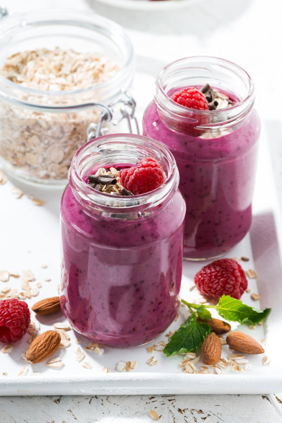 25 Easy Vitamix Smoothie Recipes To Try featuring Homemade Vitamix Raspberry Smoothies in Jars with Granola and Fresh Raspberries