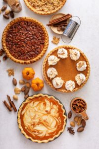 Homemade Pumpkin and Pecan Pies with Whipped Cream and Cinnamon