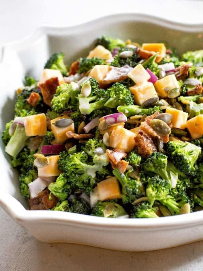 Broccoli salad with broccoli florets, bacon, cheese, onion, and sunflower/pumpkin seeds in a mayonnaise dressing. 