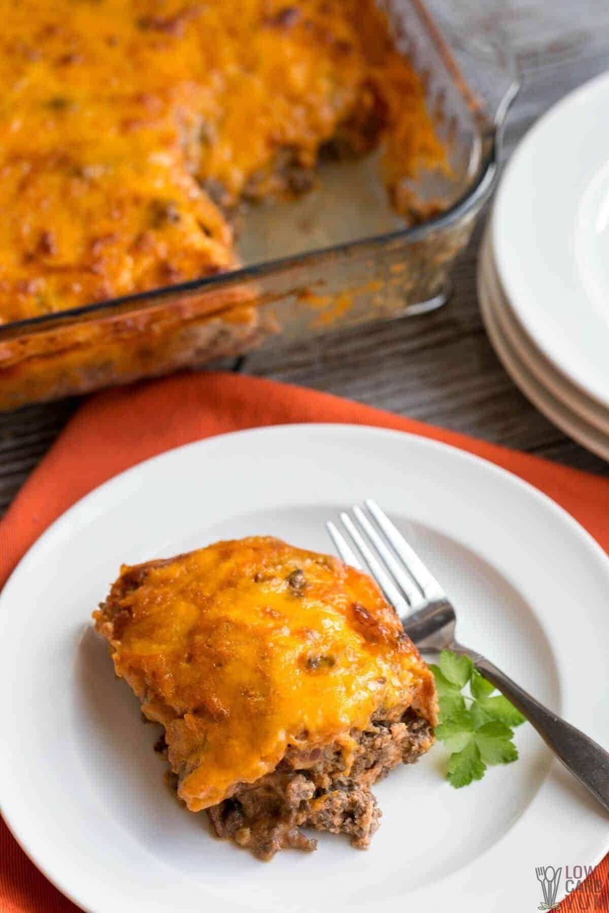 Cheeseburger casserole with bacon in plate with fork. 