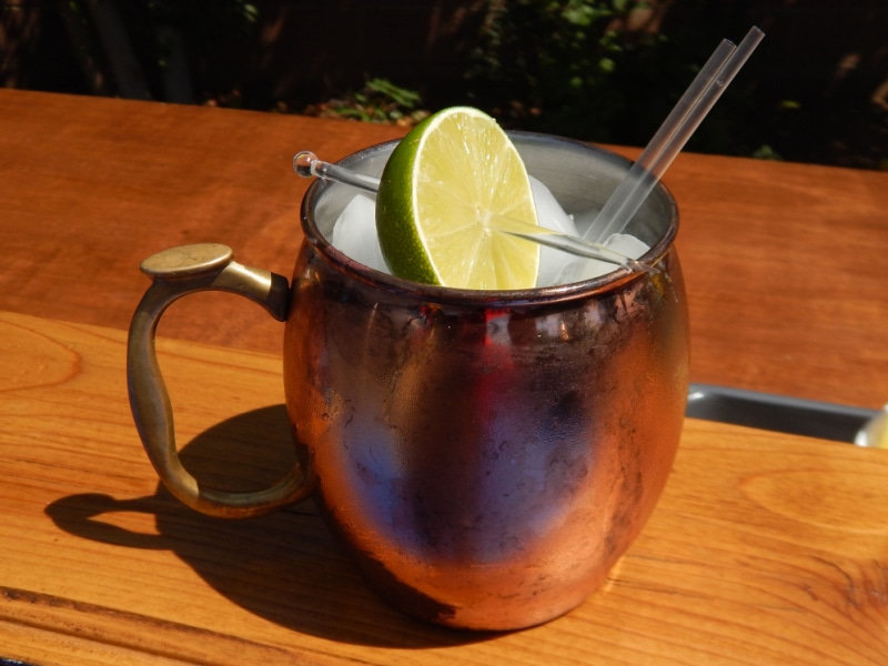 Mexican Mule Cocktail in Copper Mug Garnished with Half a Lime on a Wooden Table