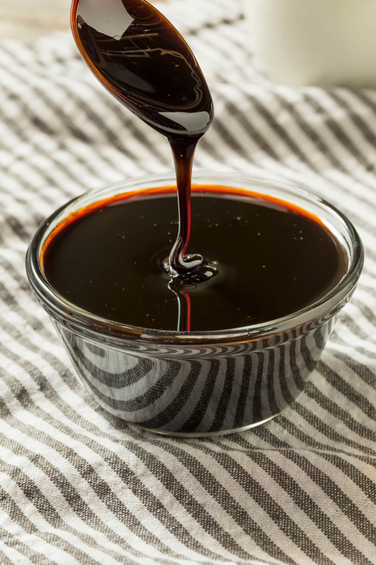Thick Molasses Syrup Dripping From a Spoon To a Small Glass Bowl