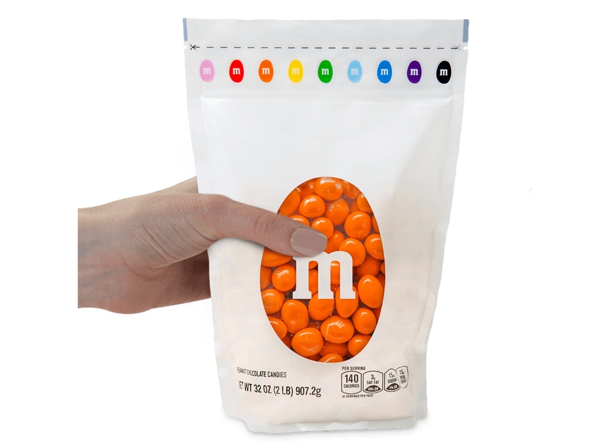 Hand Holding White Sharing Size Bag of Orange-Colored Orange Vanilla Creme M&Ms