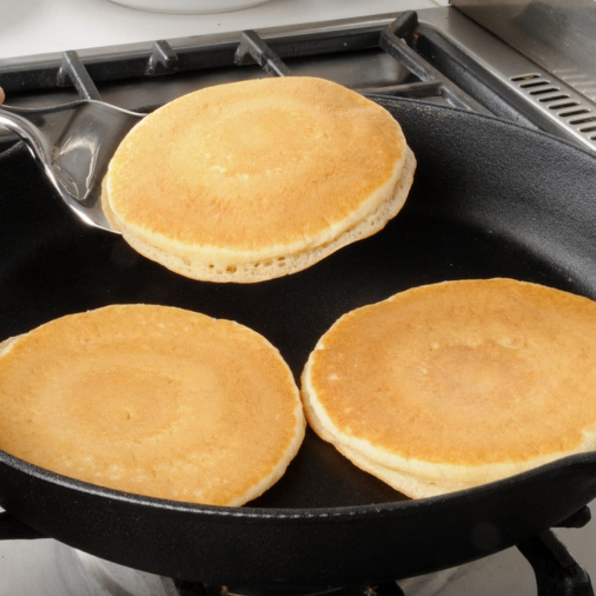 Three Pancakes Cooking in a Skillet
