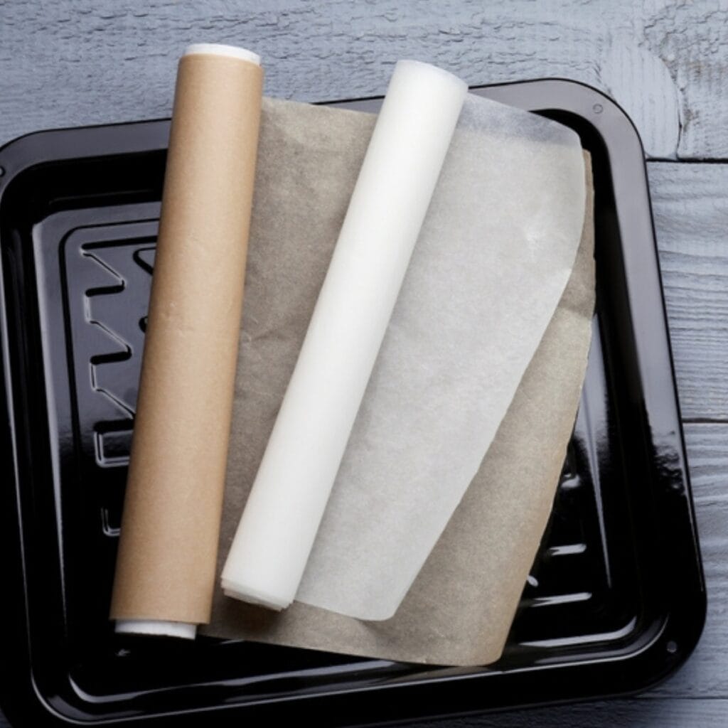 Can You Put Parchment Paper in the Oven? featuring One White and One Brown Roll of Parchment Paper and a Baking Pan