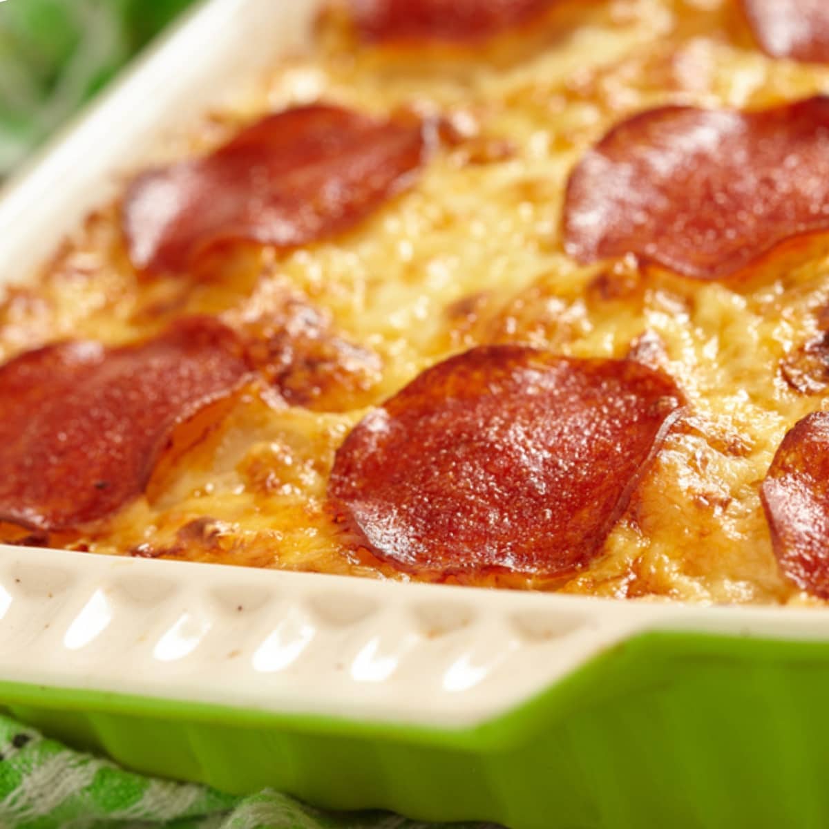Closeup pepperoni pizza casserole cooked in a green baking dish