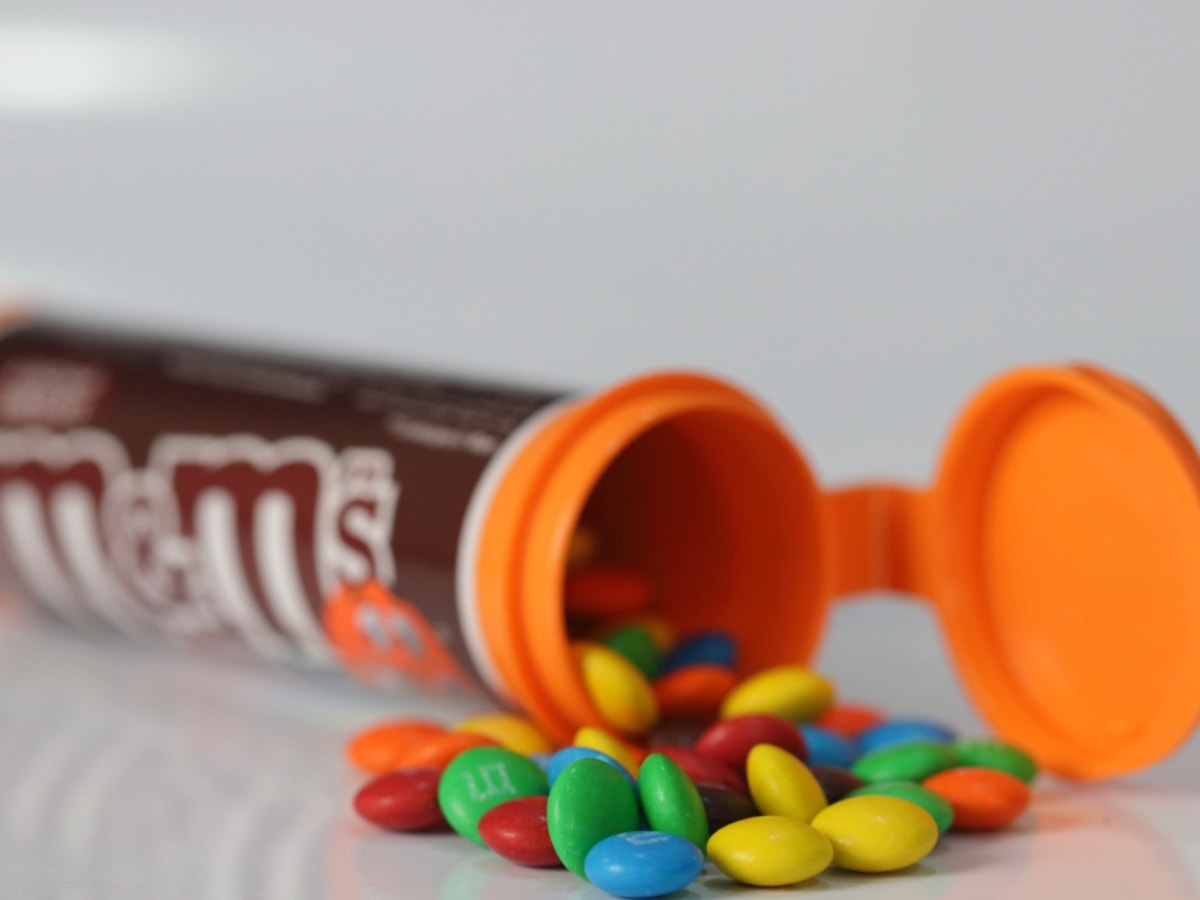 Plain Milk Chocolate M&M’s Minis in Brown and Orange Tube Spilling Out Onto Counter
