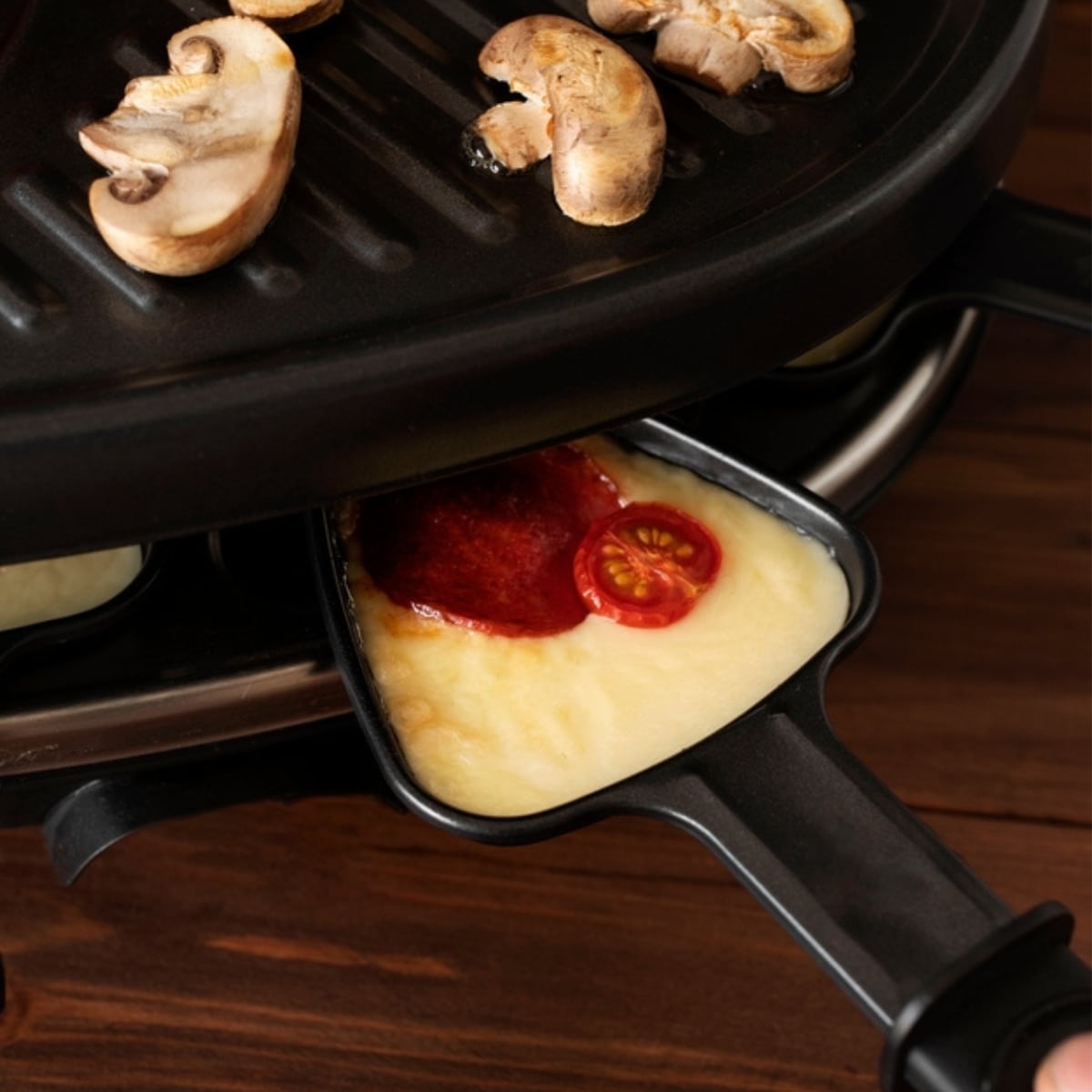 Cheese with Tomatoes and Pepperoni Cooked on a Raclette Grill with Mushrooms Grilled on Top