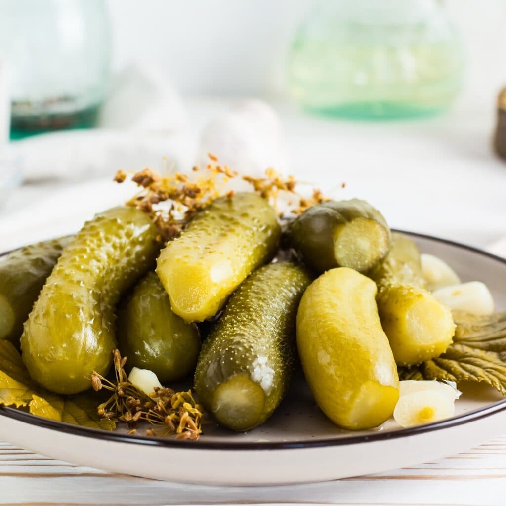 13 Types of Pickles You Have To Try 
featuring Ready to Eat Pickled Cucumbers on a Plate with Garlic and Dill
