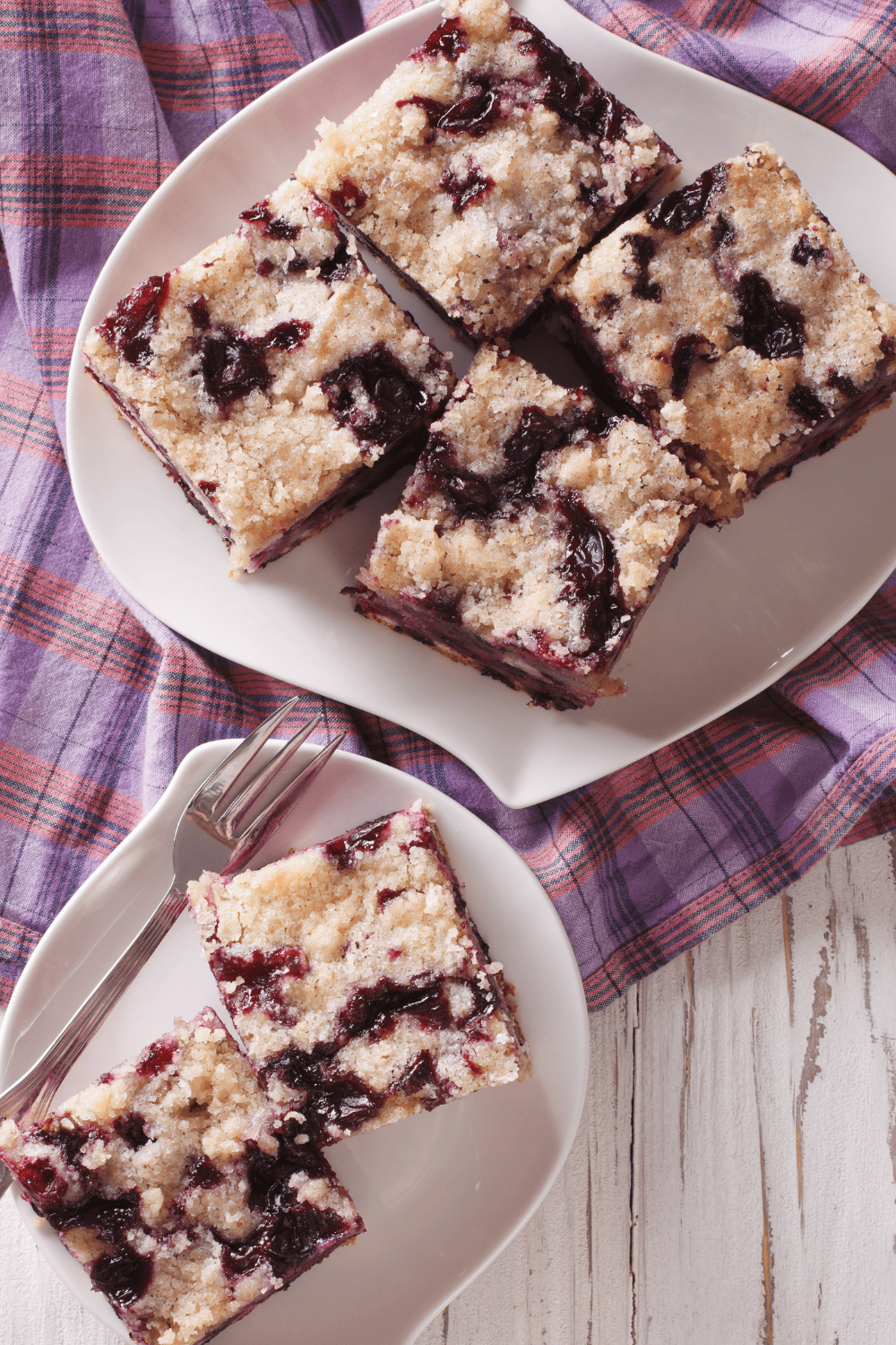 Slices of blueberry buckle on two plates with a fork
