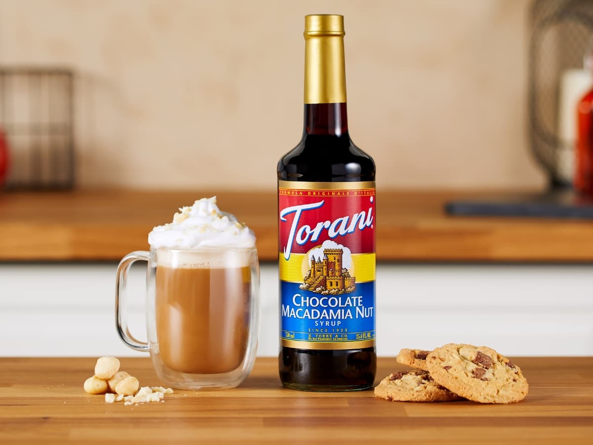 Bottle of Torani Chocolate Macadamia Nut Syrup Flavor, Glass Mug of Latte and Cookies