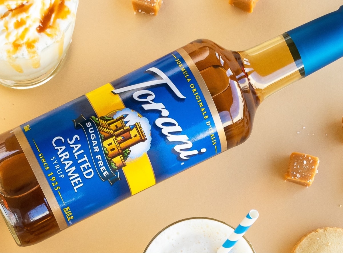 Bottle of Torani Sugar-Free Salted Caramel Syrup with Salted Caramel Candy Squares and Other Caramel Desserts Around the Bottle