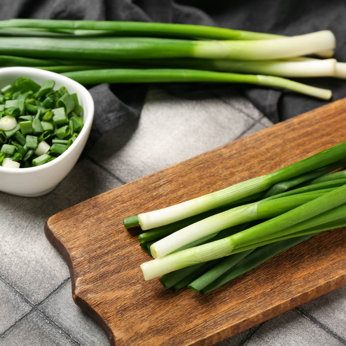 Green Onions on a Wooden Cutting Board and Slice Green Onions on a Bowl