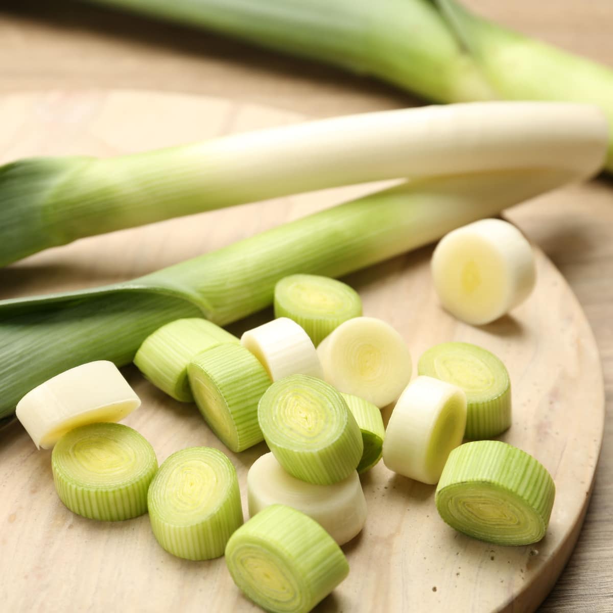 Whole and Slice Onion Leeks on a Wooden Cutting Board
