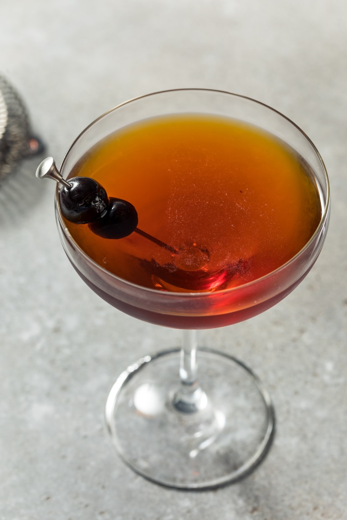 Black Manhattan Cocktail Recipe featuring Black Manhattan Cocktail in a Glass with a Black Cherry Cocktail Garnish