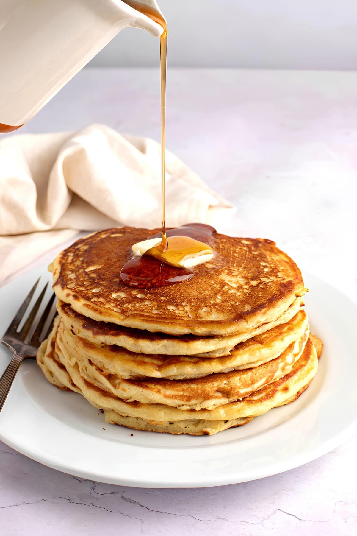 Syrup Pouring on Buttermilk Pancakes With Butter on Top