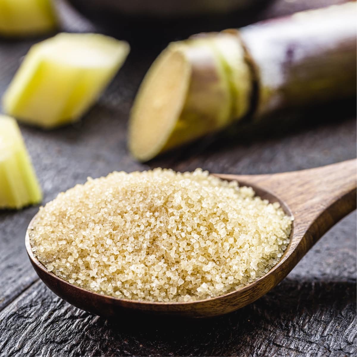 Cane Sugar on a Wooden Spoon and Raw Sugarcane
