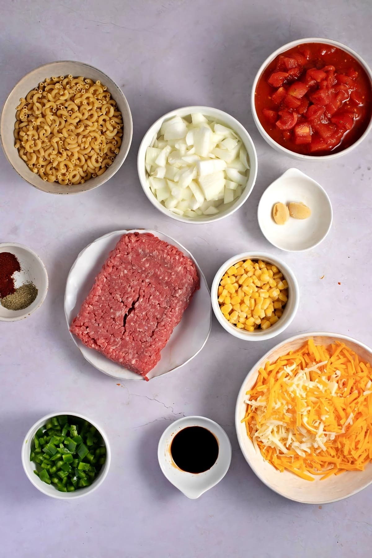Cheeseburger Casserole Ingredients - Ground Beef, Onions, Canned Diced Tomatoes, Elbow Macaroni, Corn Kernels, Green Bell Peppers, Garlic, Seasonings, Shredded Mexican Cheese Blend