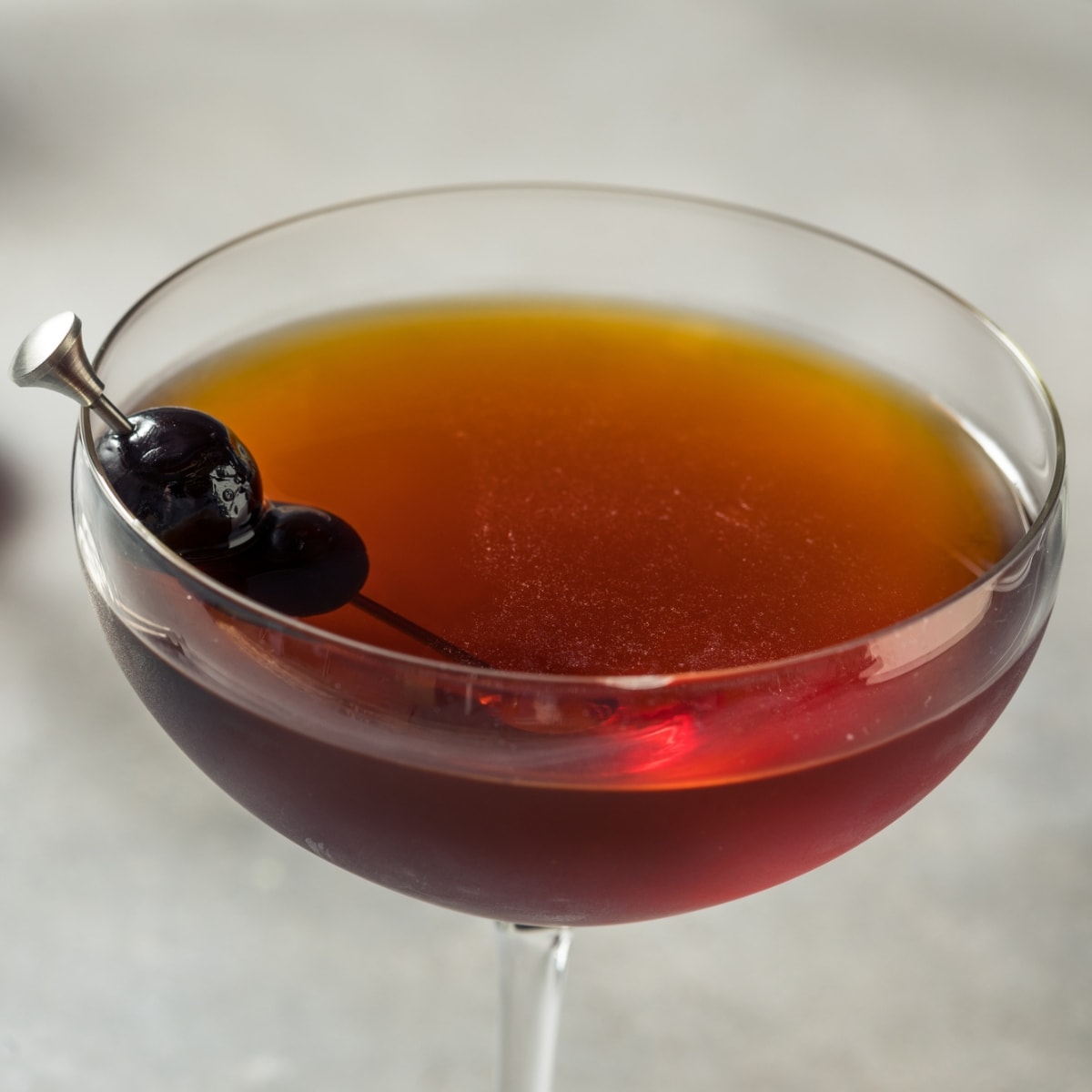 Top Side View of Glass of Black Manhattan Cocktail with Black Cherry Garnish