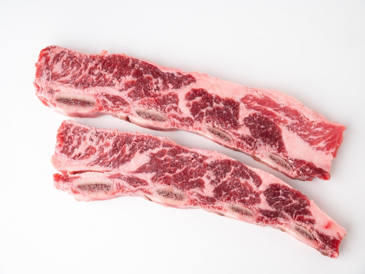 Two Raw, Flanken-Style Ribs on A White Background