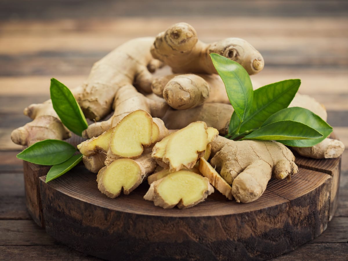 Fresh Ginger Root with Leaves on a Wooden Cutting Board