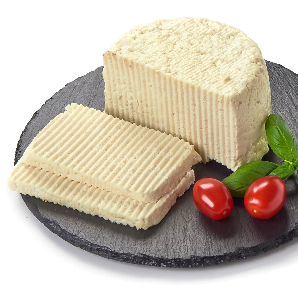 Raw Organic Havarti Cheese and Slices on a Slate Cutting Board with Basil and Tomatoes