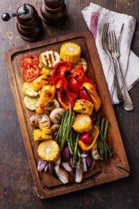 Homemade Grilled Vegetables Including Onions, Bell Peppers, Mushrooms and Green Beans in a Wooden Cutting Board