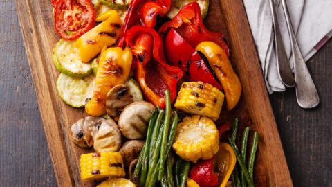 Homemade Grilled Vegetables Including Onions, Bell Peppers, Mushrooms and Green Beans in a Wooden Cutting Board