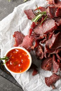 Homemade Spicy Beef Jerky with Sauce on a Parchment Paper