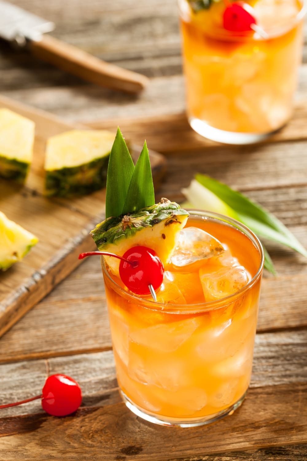 Mai Tai Cocktail Garnished With Pineapple Slices and Cherries on a Wooden Table
