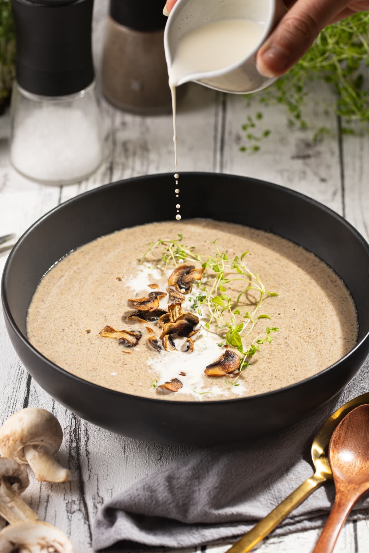 Pouring a White Milk into a Mushroom Soup with Thyme