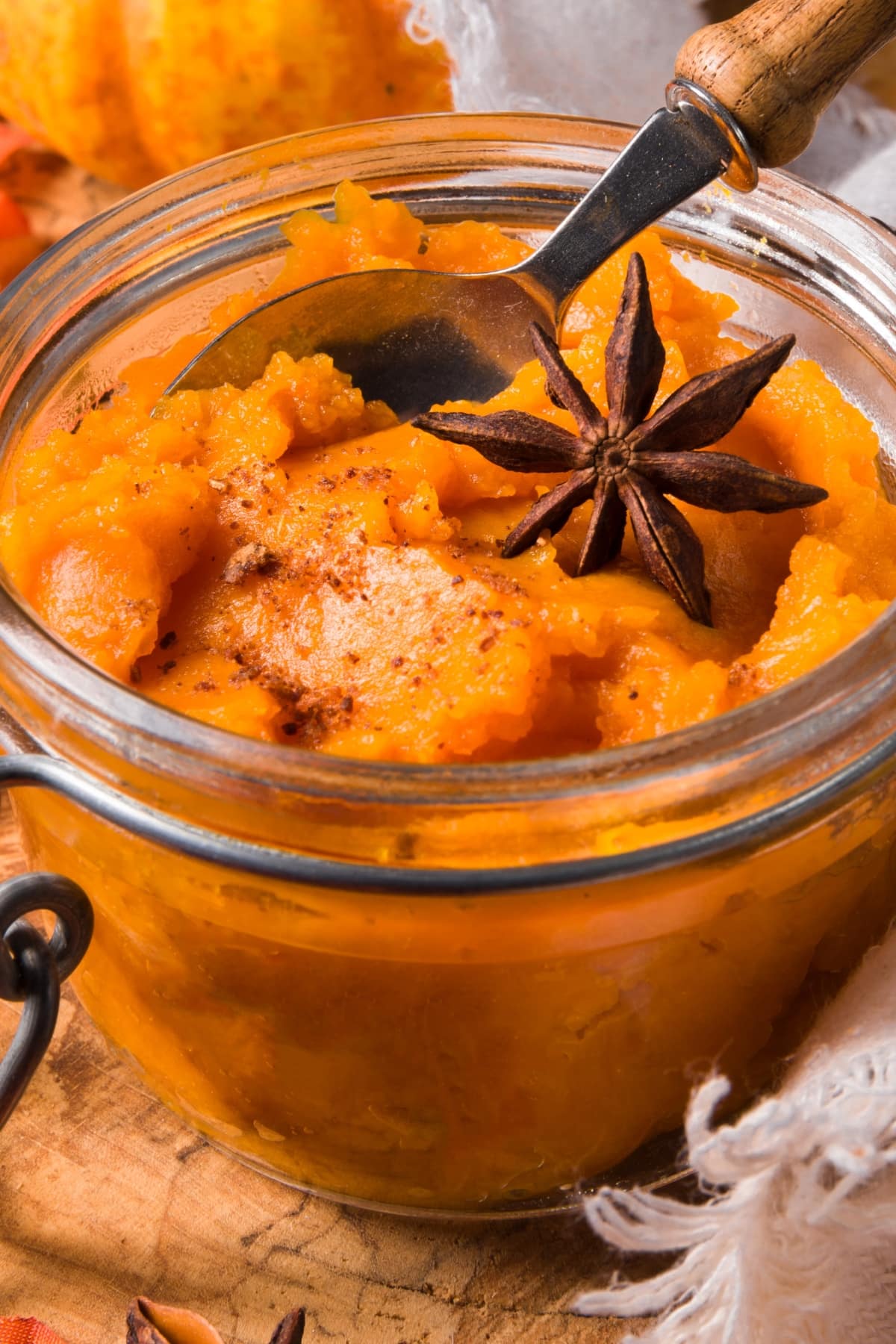 Can You Freeze Canned Pumpkin Puree? featuring Pumpkin Puree in a Glass Jar with Spoon and Cinnamon and Star Anise on Top