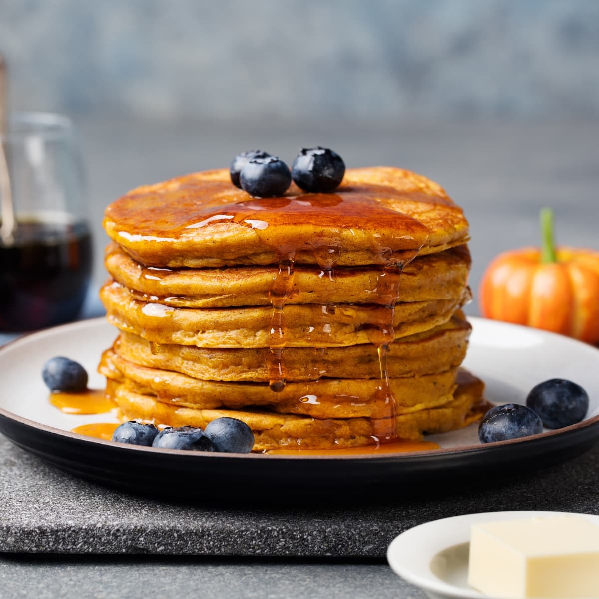 Stack of  Home Cooked Pumpkin Pancakes Drizzled With Syrup Garnished With Berries