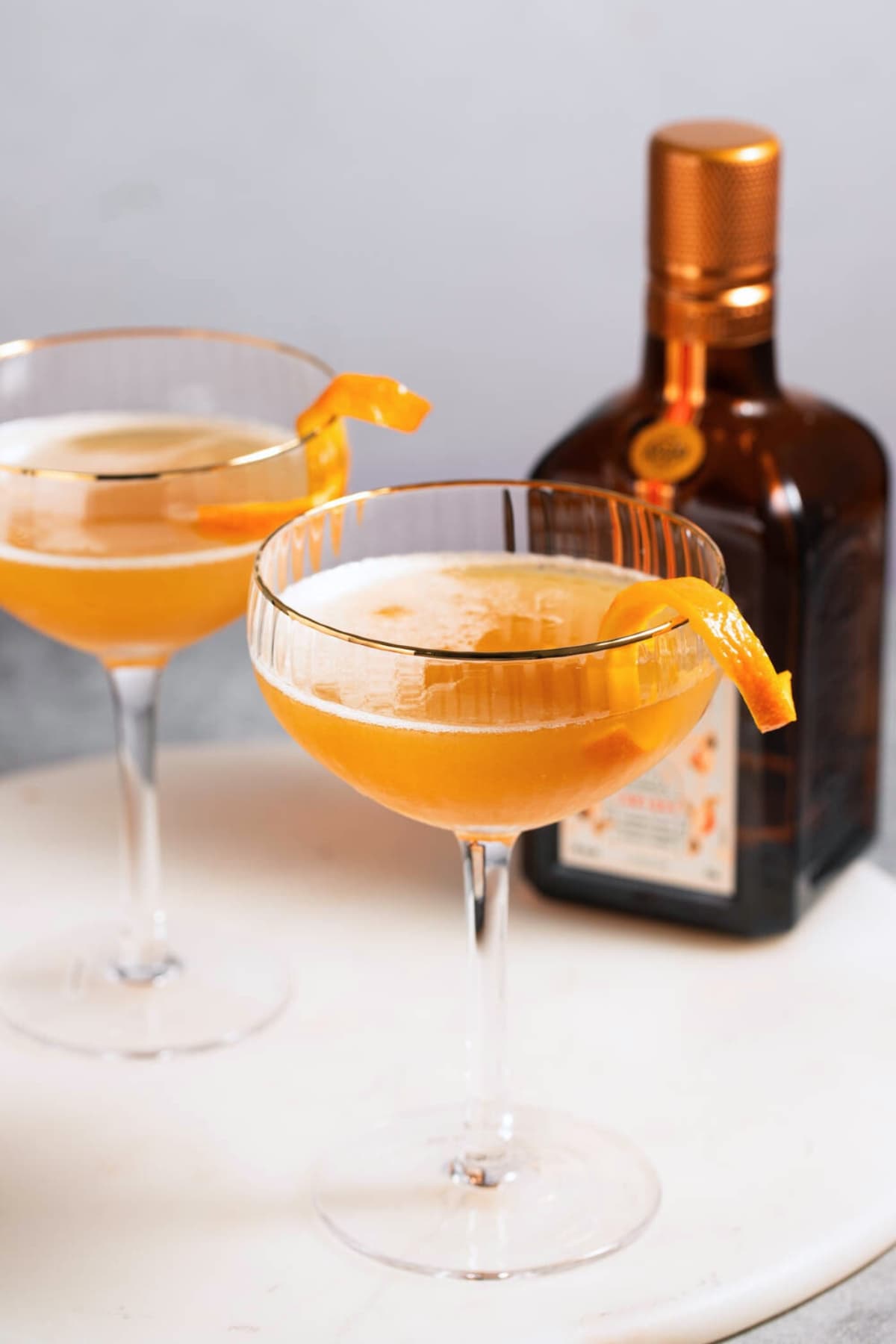 Boozy sidecar cocktail in glasses with a bottle of Cointreau