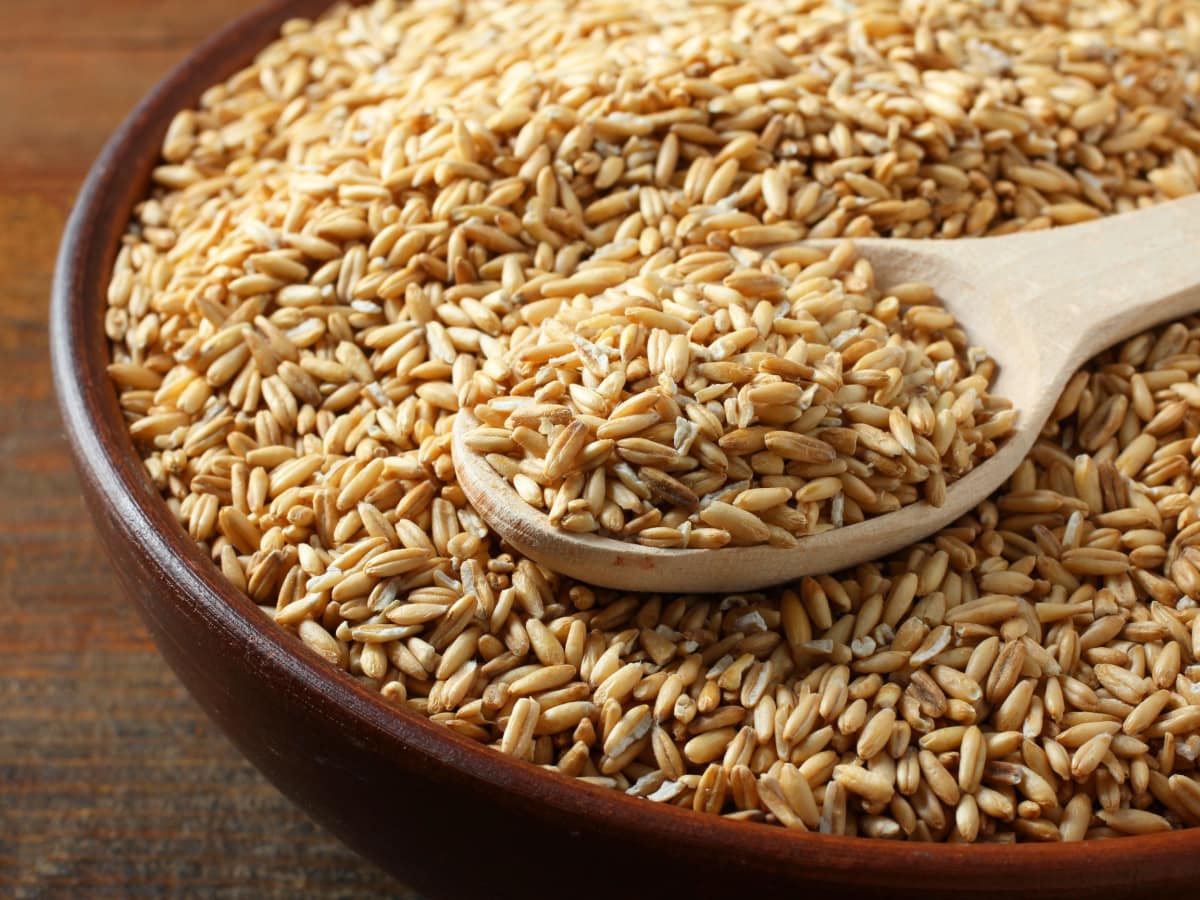 Whole Oat Groats on a Wooden Bowl with Wooden Spoon