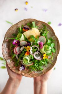 Woman Holding Summer Salad with Vegetables, Fruits, Microgreens and Cheese