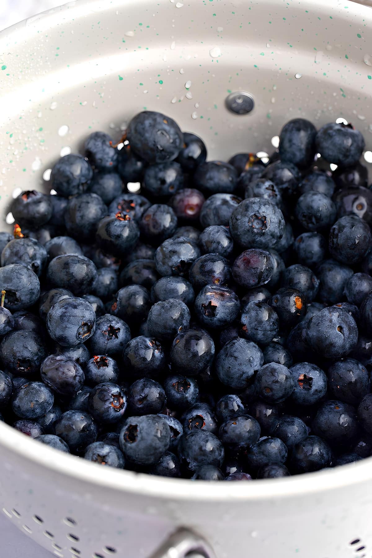 A Colander Filled with Blueberries Sitting on a Table