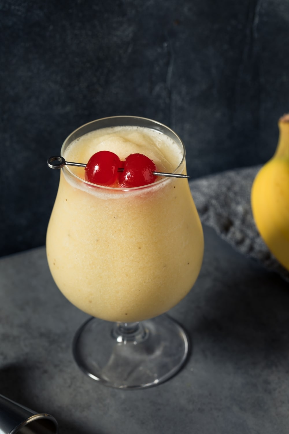  Banana Daiquiri in a Tulip Glass with a Jigger and Banana on the Side, Garnished With Cherries
