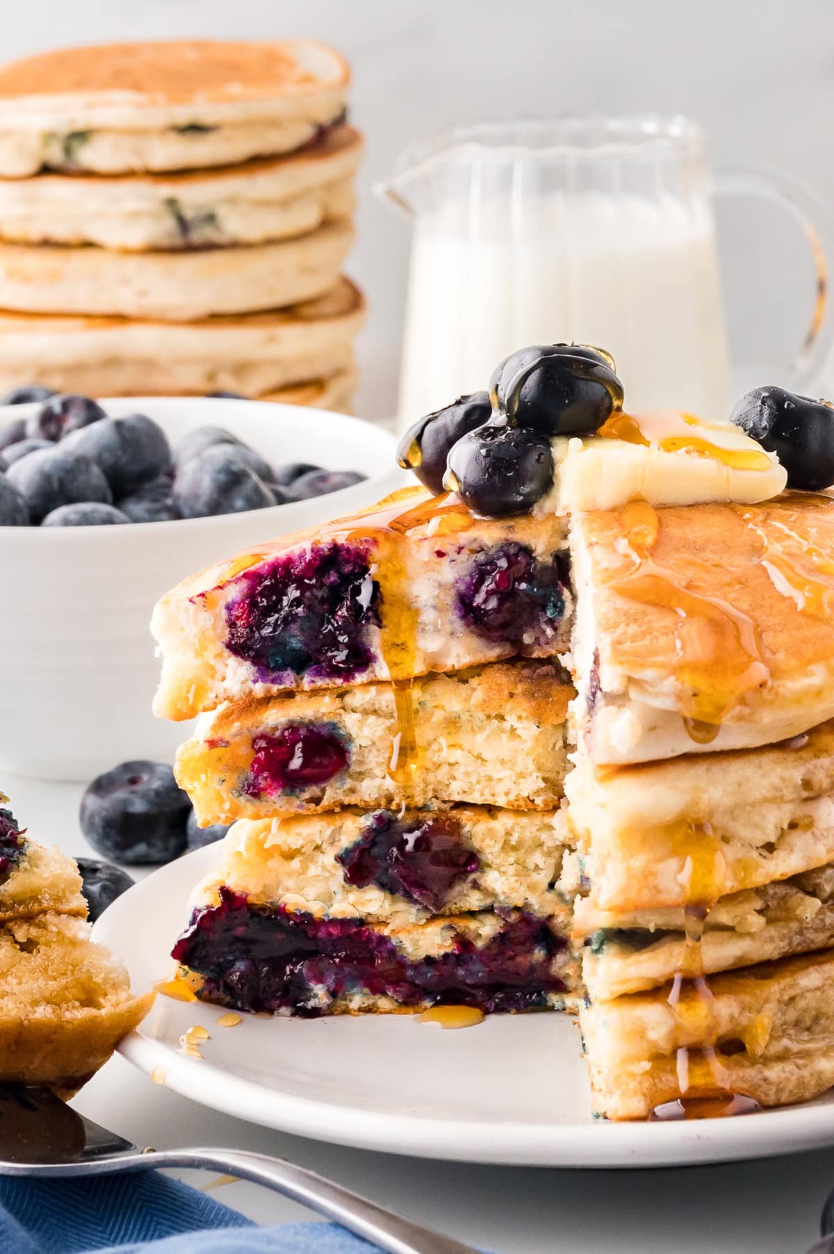A stack of blueberry pancakes with a wedge cut out.