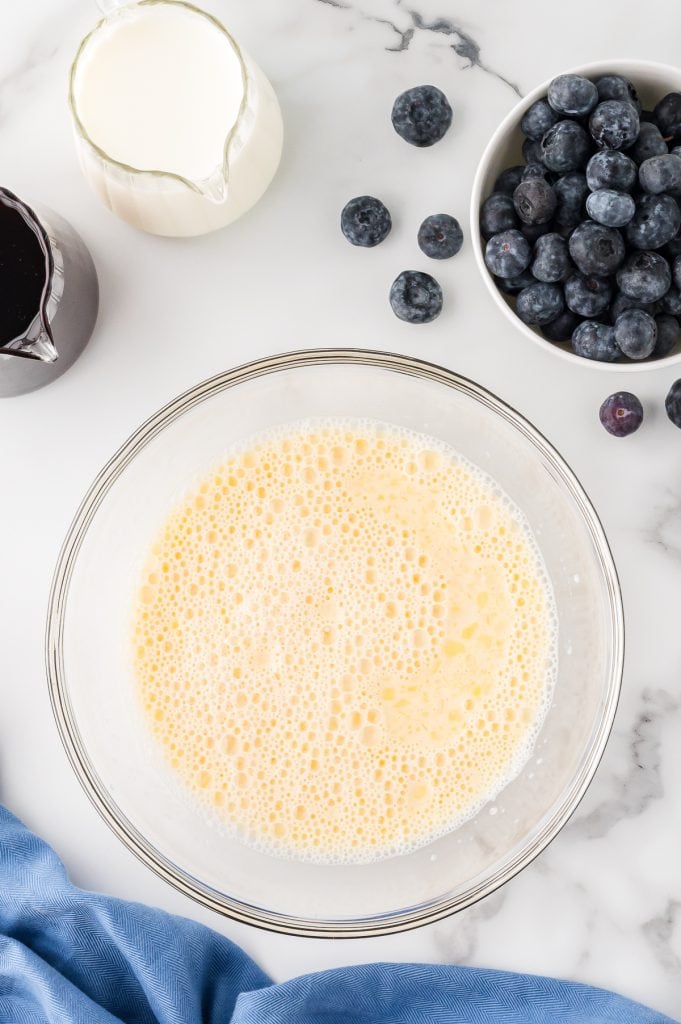 A mixture of beaten egg, milk, melted butter, and vanilla extract in a glass bowl.