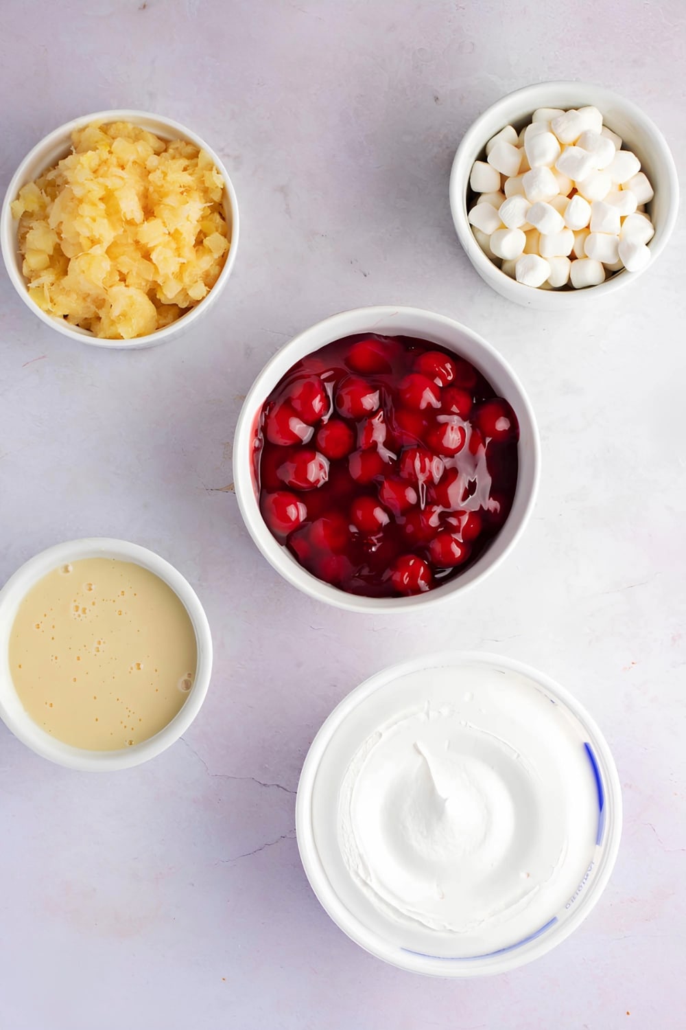 Cherry Fluff Ingredients- Bowls of Diced Pineapples, Marshmallows, Cherries, Condensed Milk, and Whip Cream