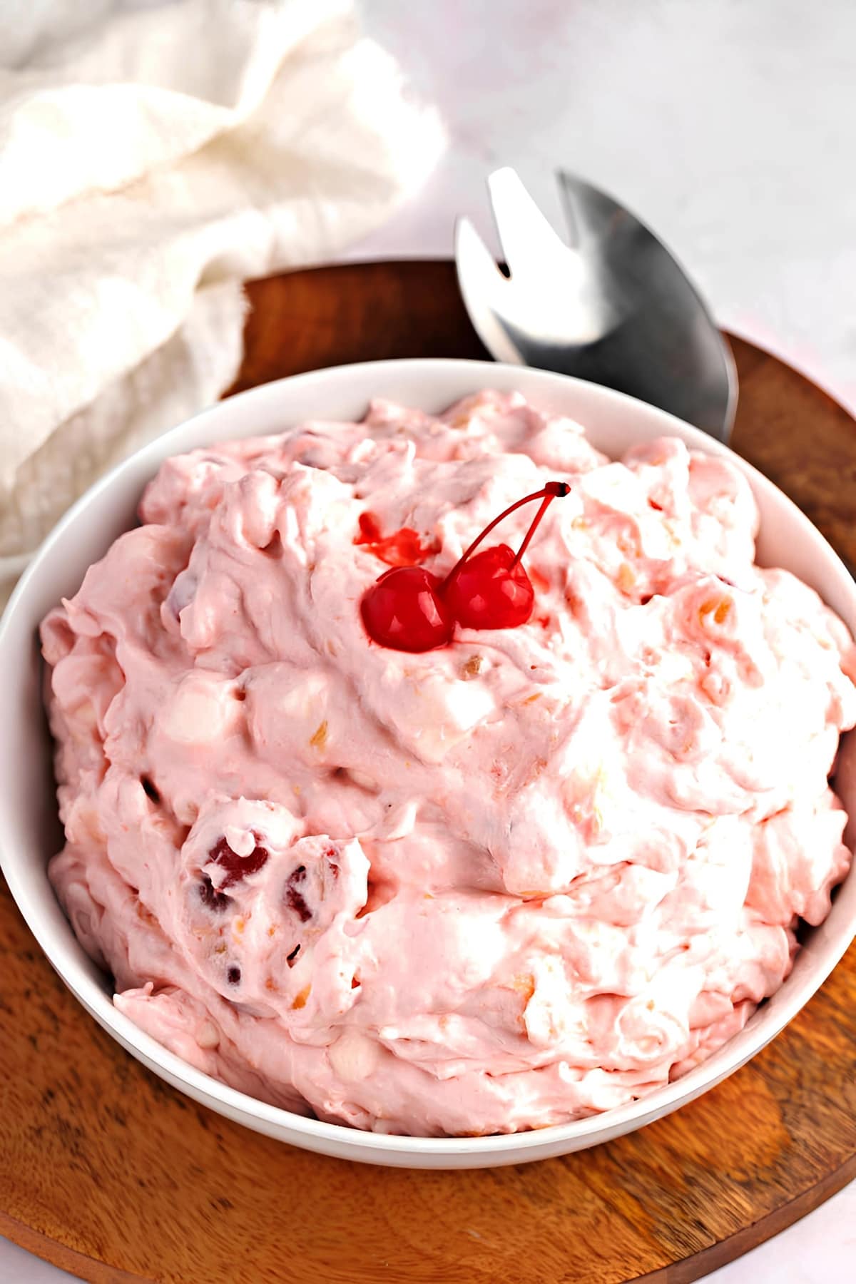Best Cherry Fluff (Easy Dessert Salad) featuring Cherry Fluff in a White Bowl on a Wooden Cutting Board