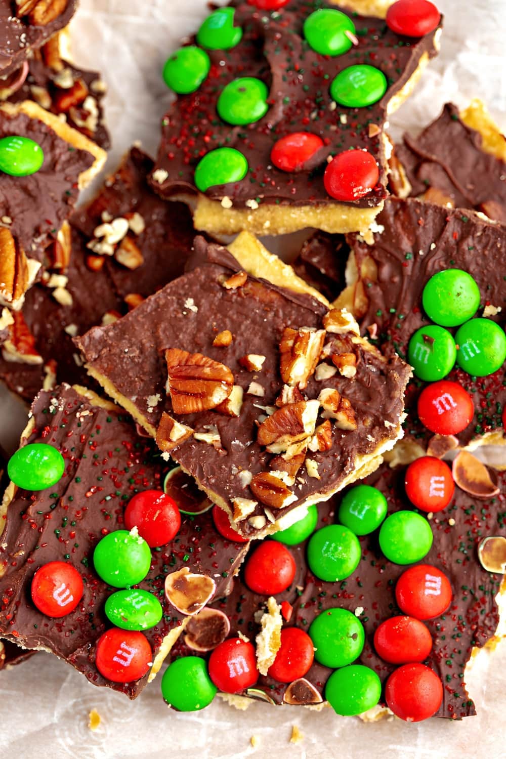 Top view of Christmas crack covered in chocolate and topped with pecan nuts and M&M's candies. 