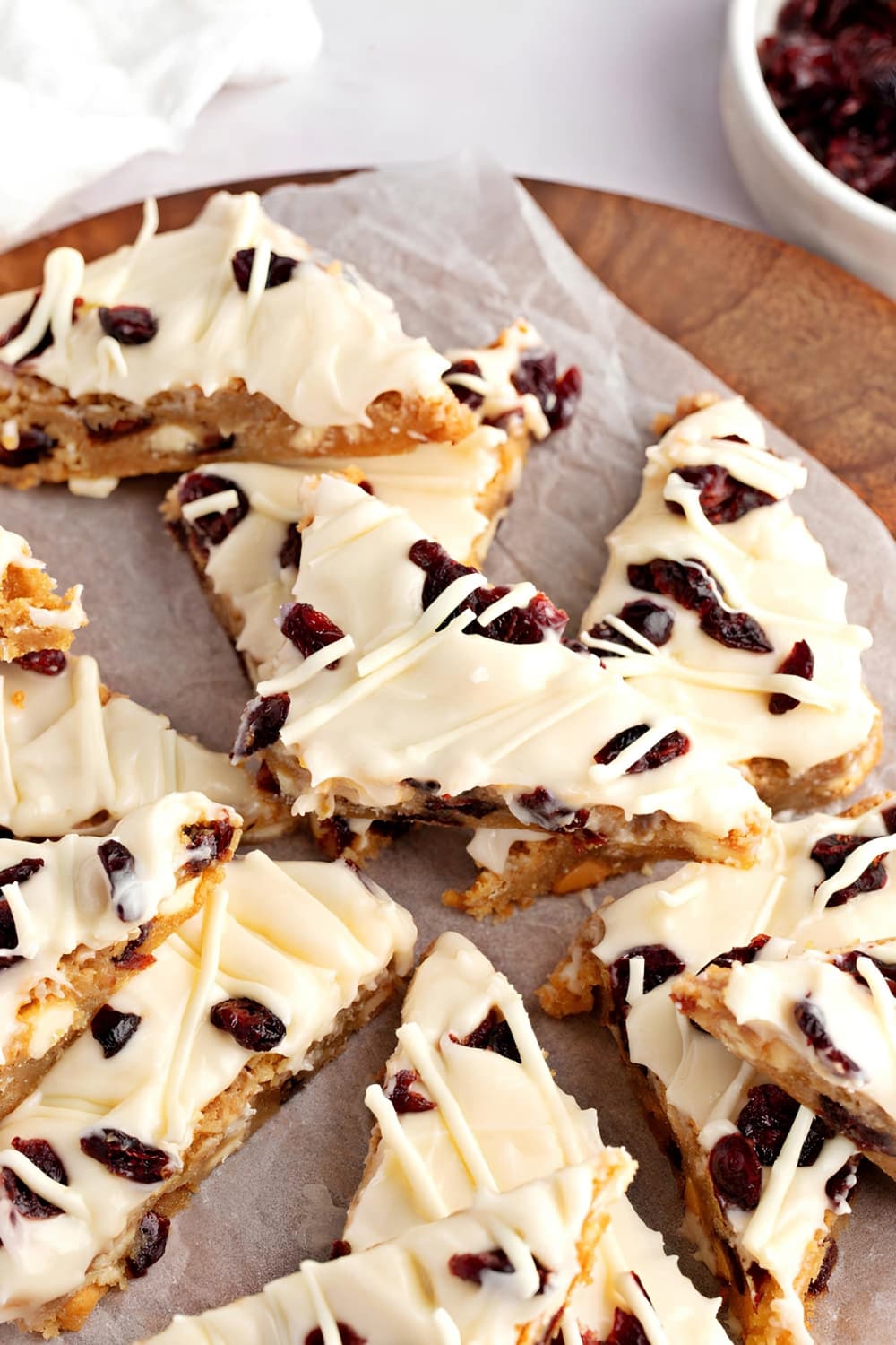 Sliced bars with cranberries topped with frosting and chocolate syrup.