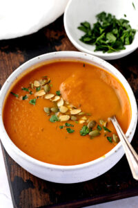 Creamy Pumpkin Soup in a Bowl with Seeds and Herbs
