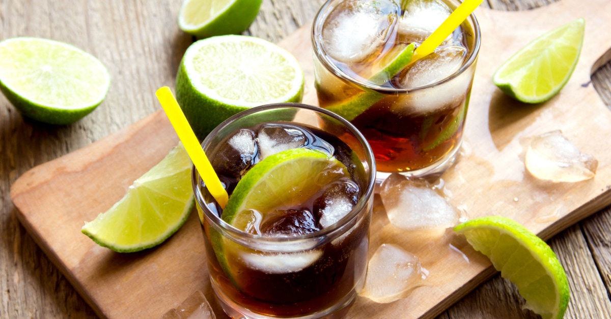 Cuba Libre with Ice and Lime in Glasses on a Wooden Board